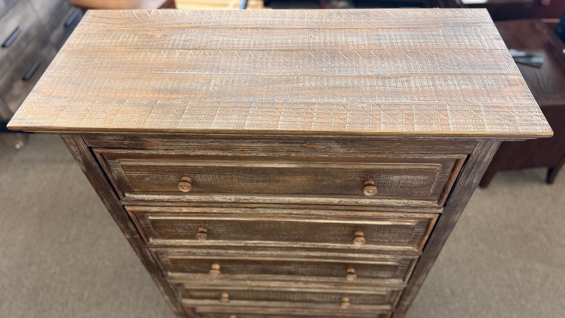 A tall rustic 5-drawer chest of drawers featuring a weathered white-washed finish over dark wood, a crown-molding top, and pairs of round matching knobs.