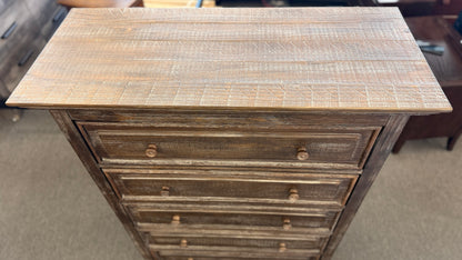A tall rustic 5-drawer chest of drawers featuring a weathered white-washed finish over dark wood, a crown-molding top, and pairs of round matching knobs.