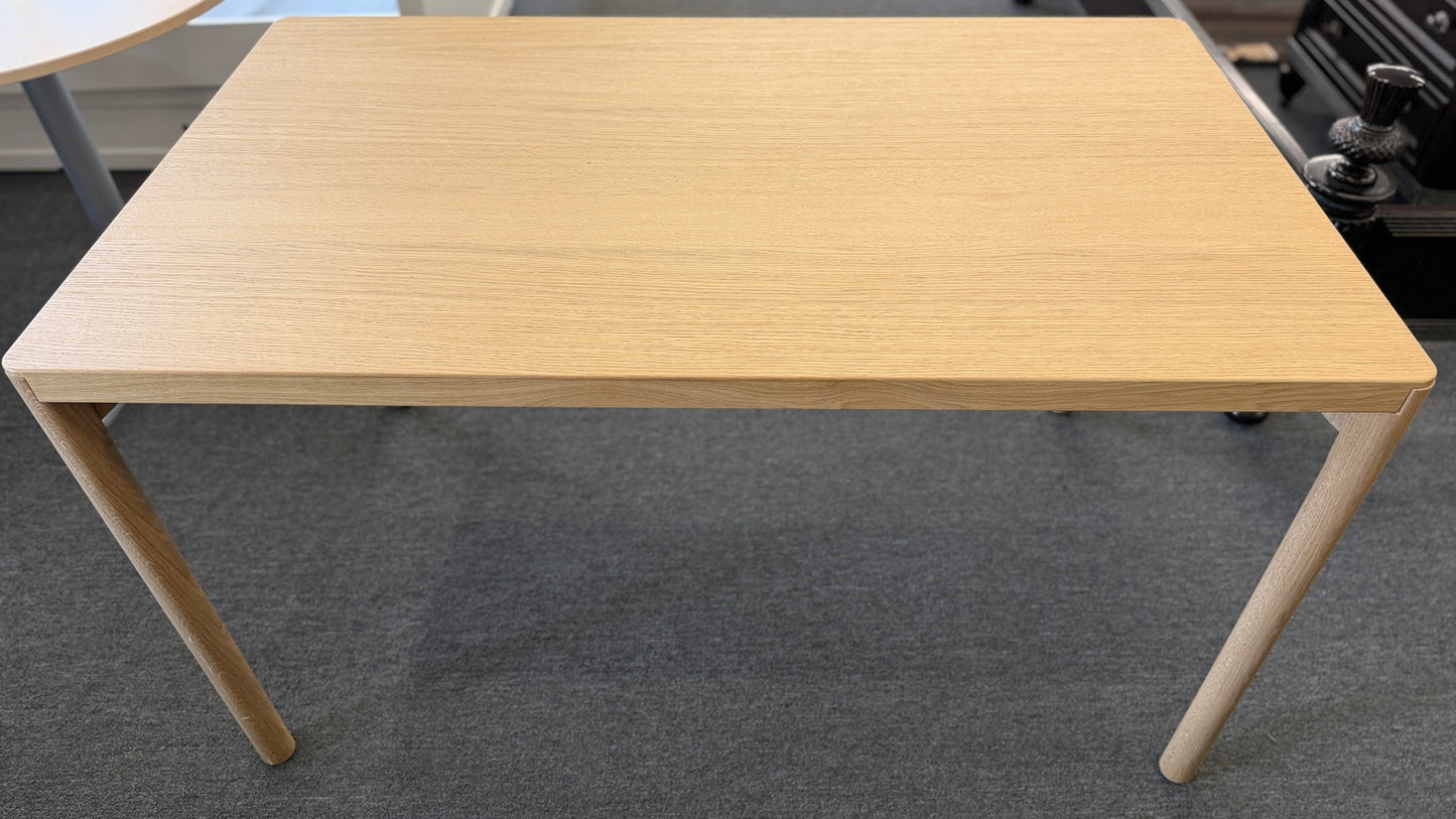 Scandinavian-style light wood writing desk featuring a rectangular tabletop with rounded corners and slightly splayed cylindrical wooden legs.