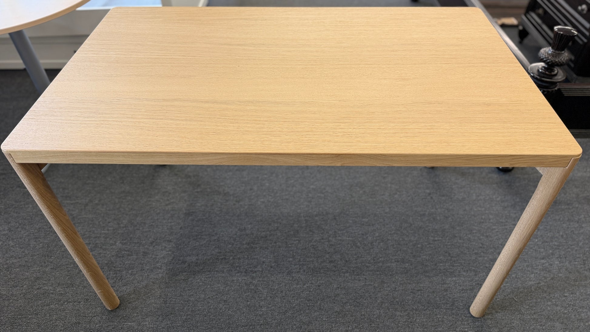 Scandinavian-style light wood writing desk featuring a rectangular tabletop with rounded corners and slightly splayed cylindrical wooden legs.