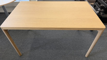 Scandinavian-style light wood writing desk featuring a rectangular tabletop with rounded corners and slightly splayed cylindrical wooden legs.