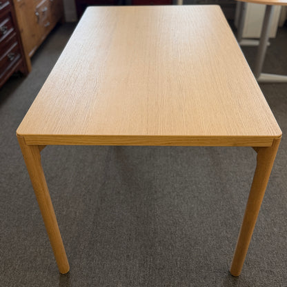 Scandinavian-style light wood writing desk featuring a rectangular tabletop with rounded corners and slightly splayed cylindrical wooden legs.