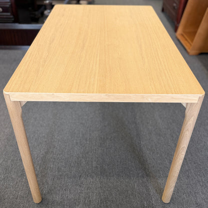 Scandinavian-style light wood writing desk featuring a rectangular tabletop with rounded corners and slightly splayed cylindrical wooden legs.