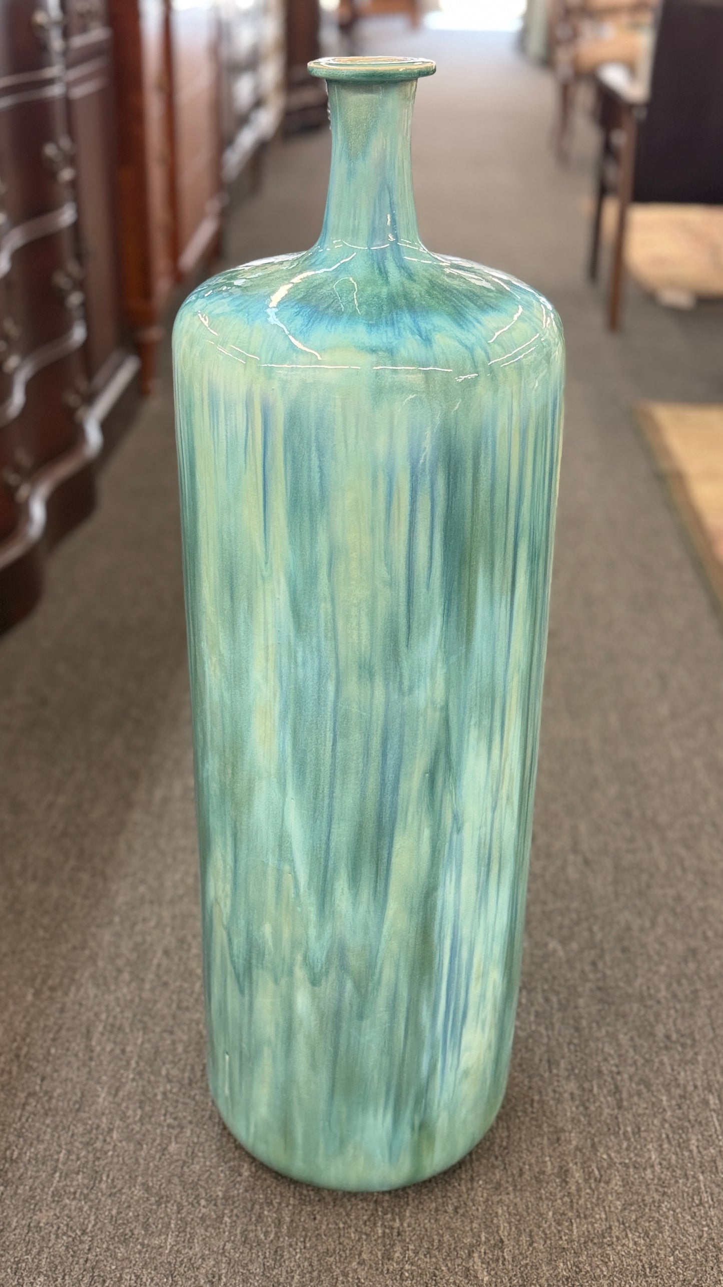 A tall, large cylindrical ceramic floor vase with a narrow neck, featuring a glossy, vertically streaked drip-glaze finish in seafoam green, aqua, and pale blue.