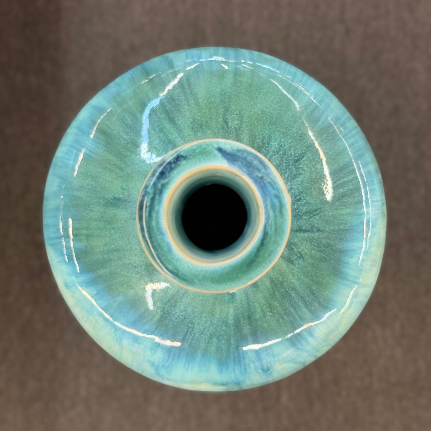 A tall, large cylindrical ceramic floor vase with a narrow neck, featuring a glossy, vertically streaked drip-glaze finish in seafoam green, aqua, and pale blue.