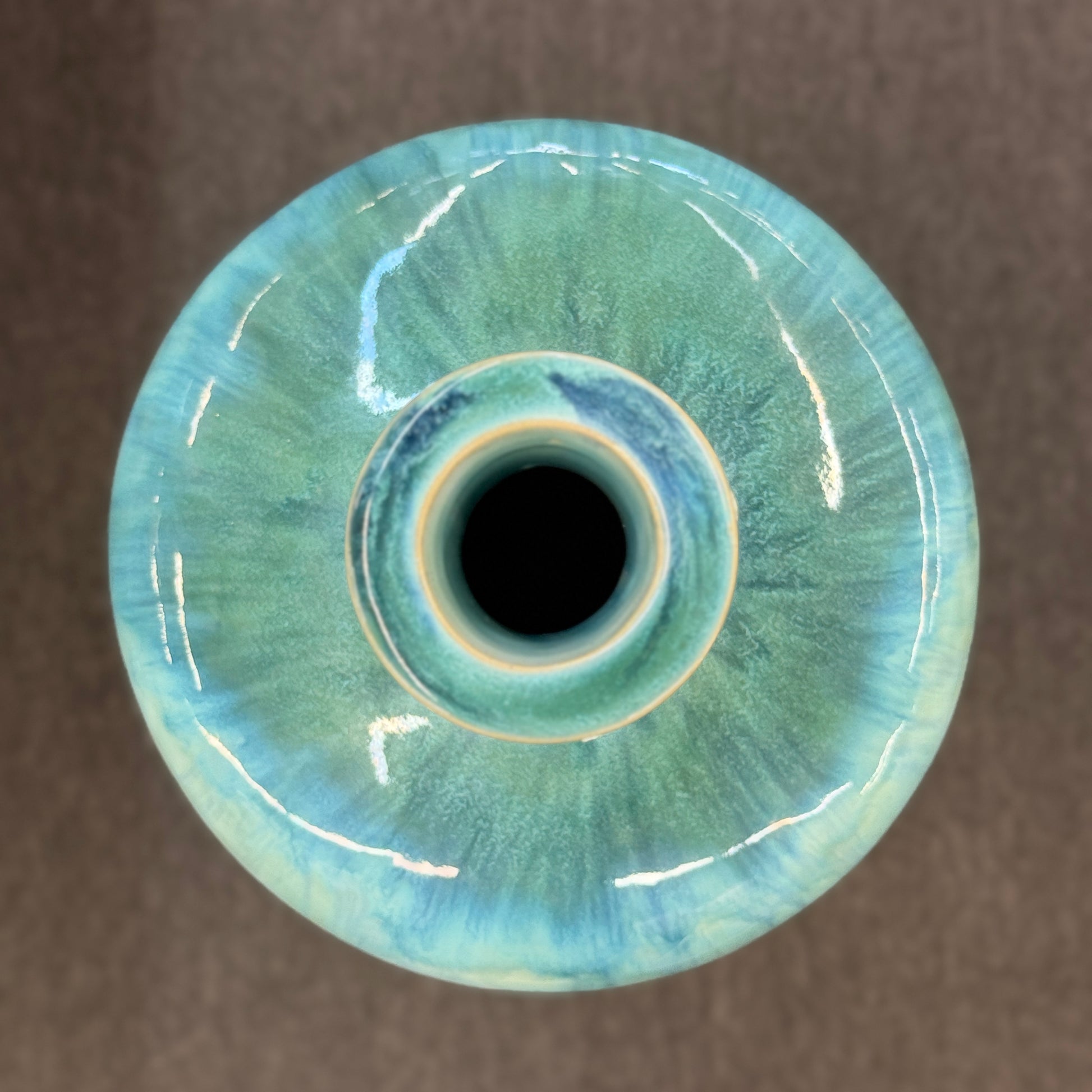A tall, large cylindrical ceramic floor vase with a narrow neck, featuring a glossy, vertically streaked drip-glaze finish in seafoam green, aqua, and pale blue.