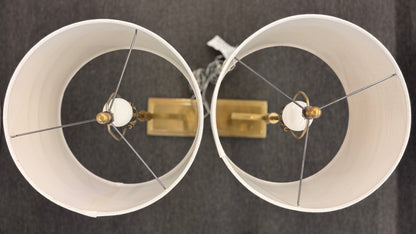 Matching pair of contemporary brass table lamps featuring stepped rectangular bases, angular geometric stems, and white fabric drum shades.