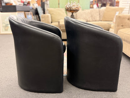 Set of two modern black barrel accent chairs featuring wraparound curved backs, thick integrated seat cushions, and a clean contemporary design.