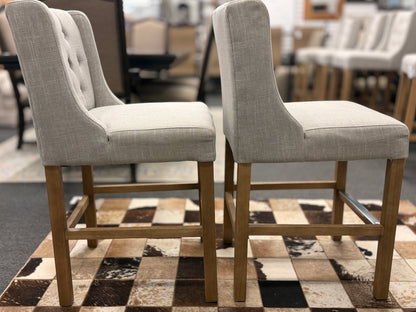 Set of two upholstered bar stools featuring wood and metal construction with comfortable fabric seats for kitchen islands or home bars.