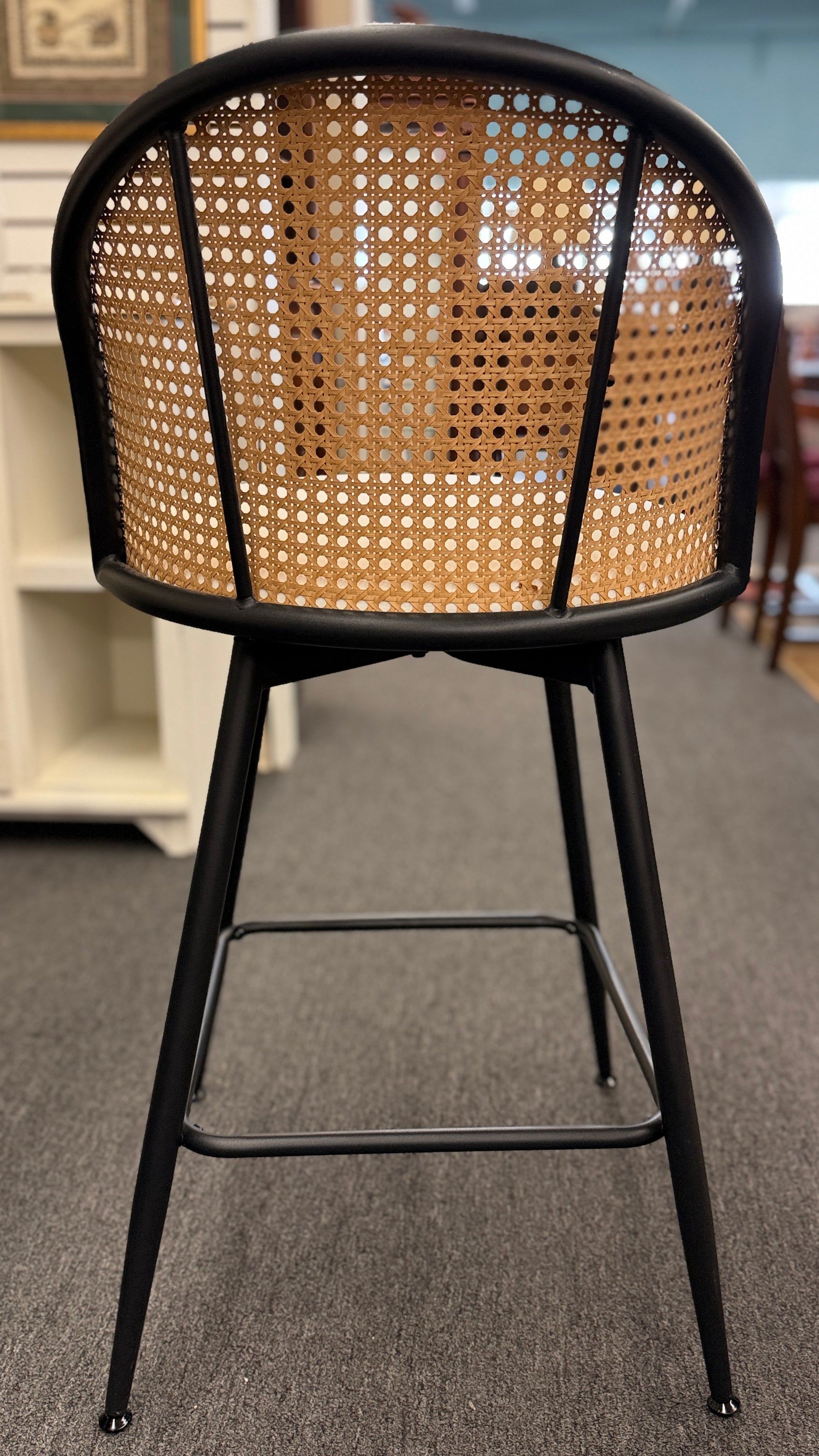 Set of three counter-height bar stools featuring curved woven cane backrests, white upholstered seat cushions, and black metal legs with built-in footrests.