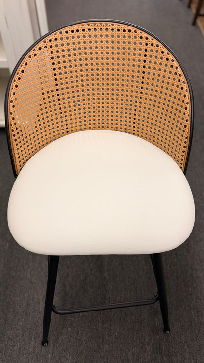 Set of three counter-height bar stools featuring curved woven cane backrests, white upholstered seat cushions, and black metal legs with built-in footrests.