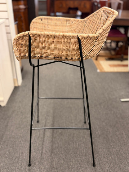 Set of three modern bar stools featuring woven rattan bucket-style seats, slim black iron frames, and built-in footrests.