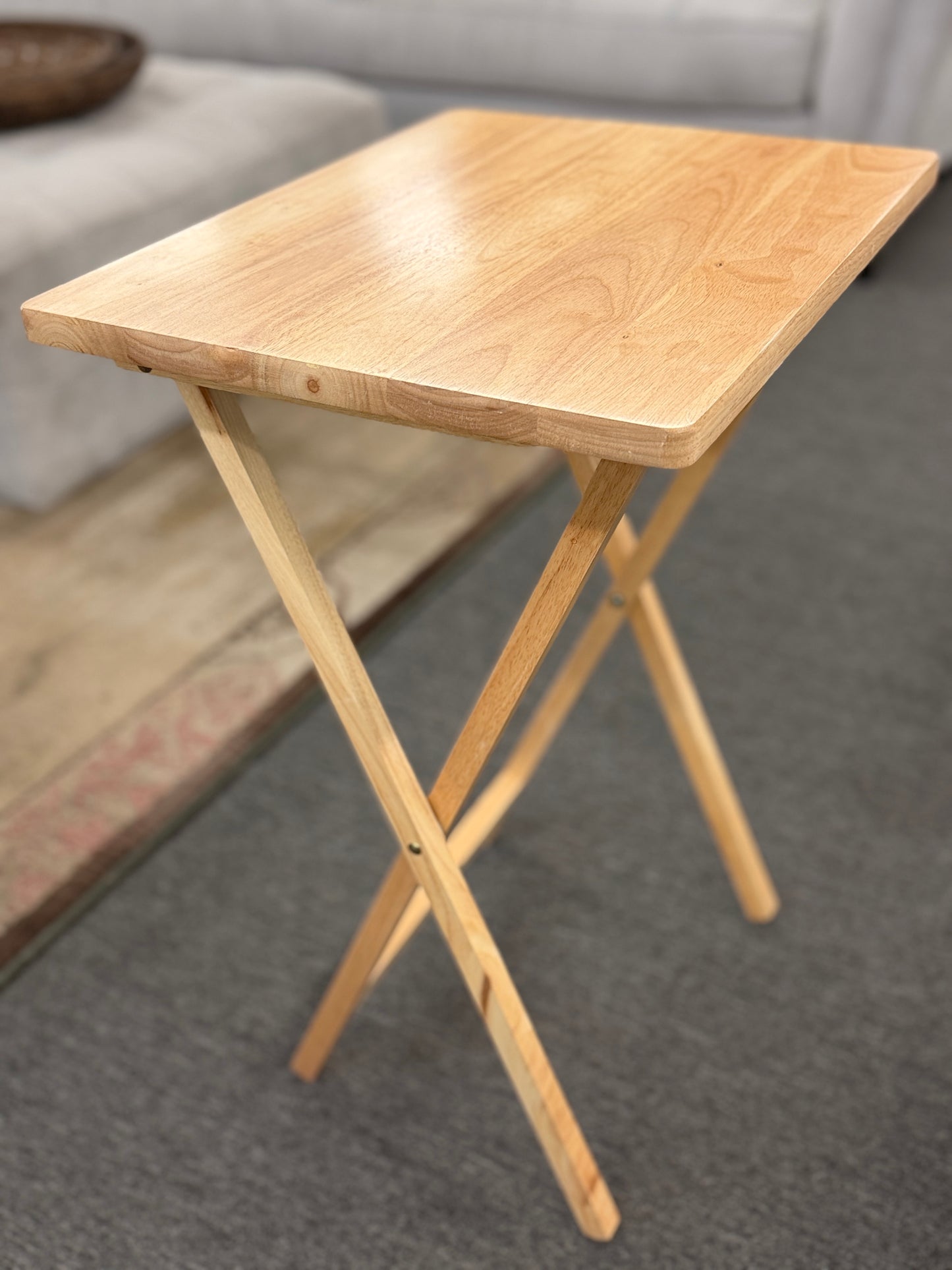 Set of four light wood folding TV tray tables stored on a matching wooden stand for compact, space-saving storage.
