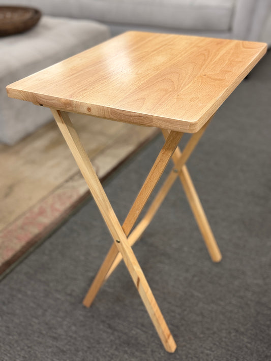 Set of four light wood folding TV tray tables stored on a matching wooden stand for compact, space-saving storage.