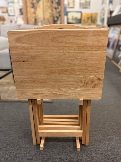 Set of four light wood folding TV tray tables stored on a matching wooden stand for compact, space-saving storage.