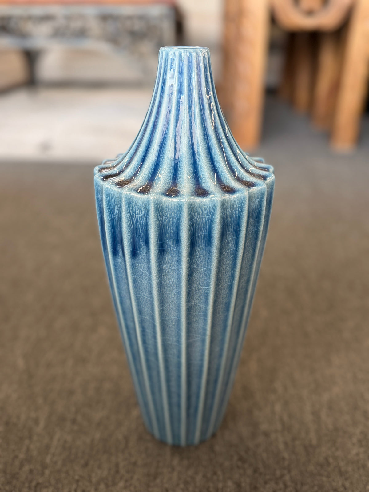 A slender ceramic vase finished in a crackle-glaze slate-blue hue with vertical fluted ridges tapering to a narrow neck in excellent condition.