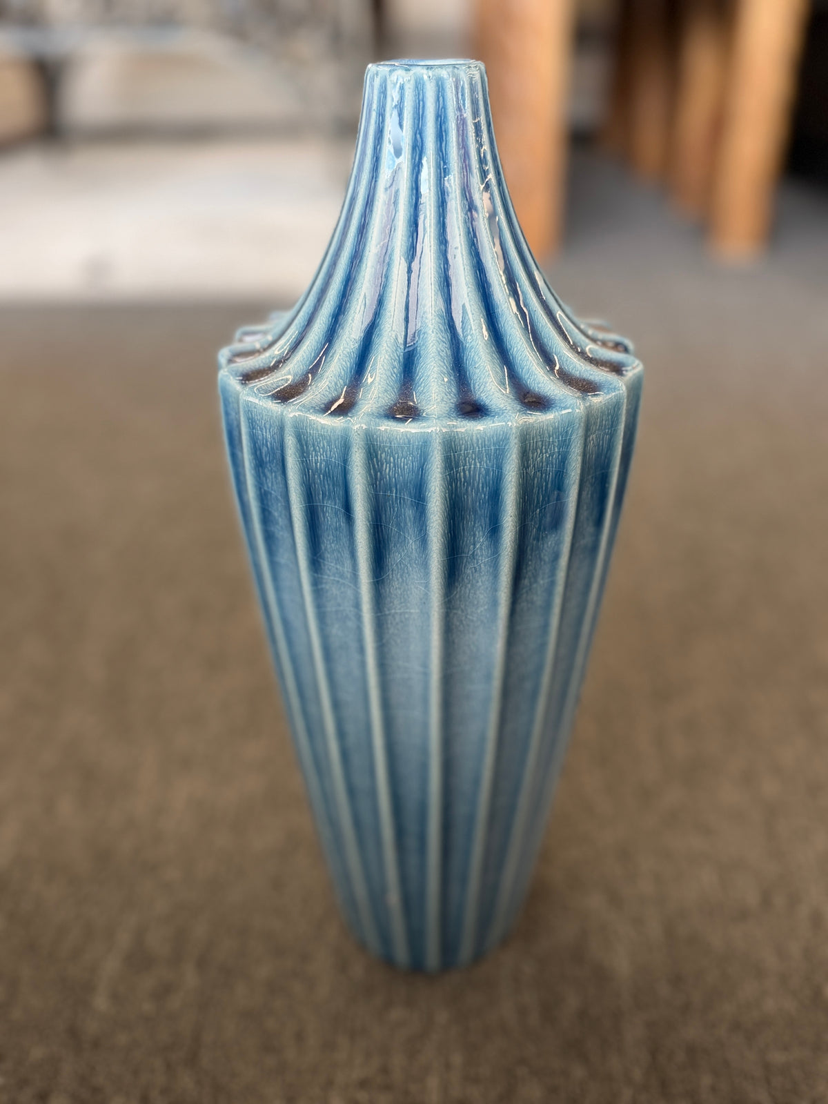 A slender ceramic vase finished in a crackle-glaze slate-blue hue with vertical fluted ridges tapering to a narrow neck in excellent condition.