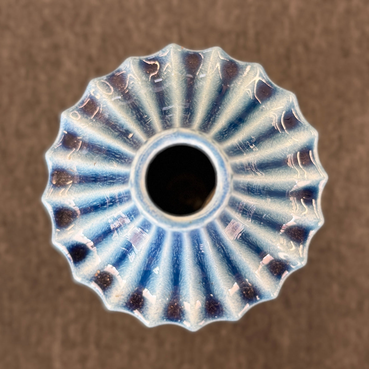 A slender ceramic vase finished in a crackle-glaze slate-blue hue with vertical fluted ridges tapering to a narrow neck in excellent condition.