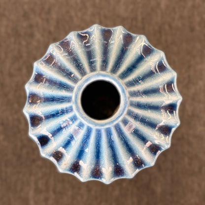 A slender ceramic vase finished in a crackle-glaze slate-blue hue with vertical fluted ridges tapering to a narrow neck in excellent condition.