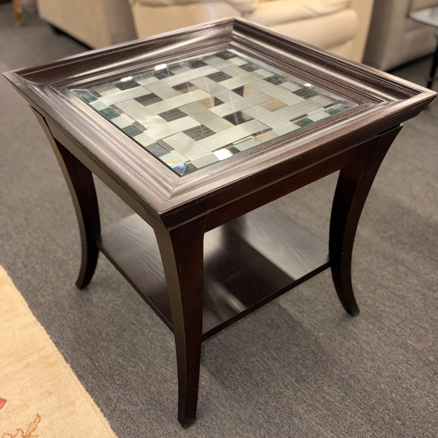 Square dark wood end table featuring a glass top with an intricate woven metal inlay and a lower display shelf.