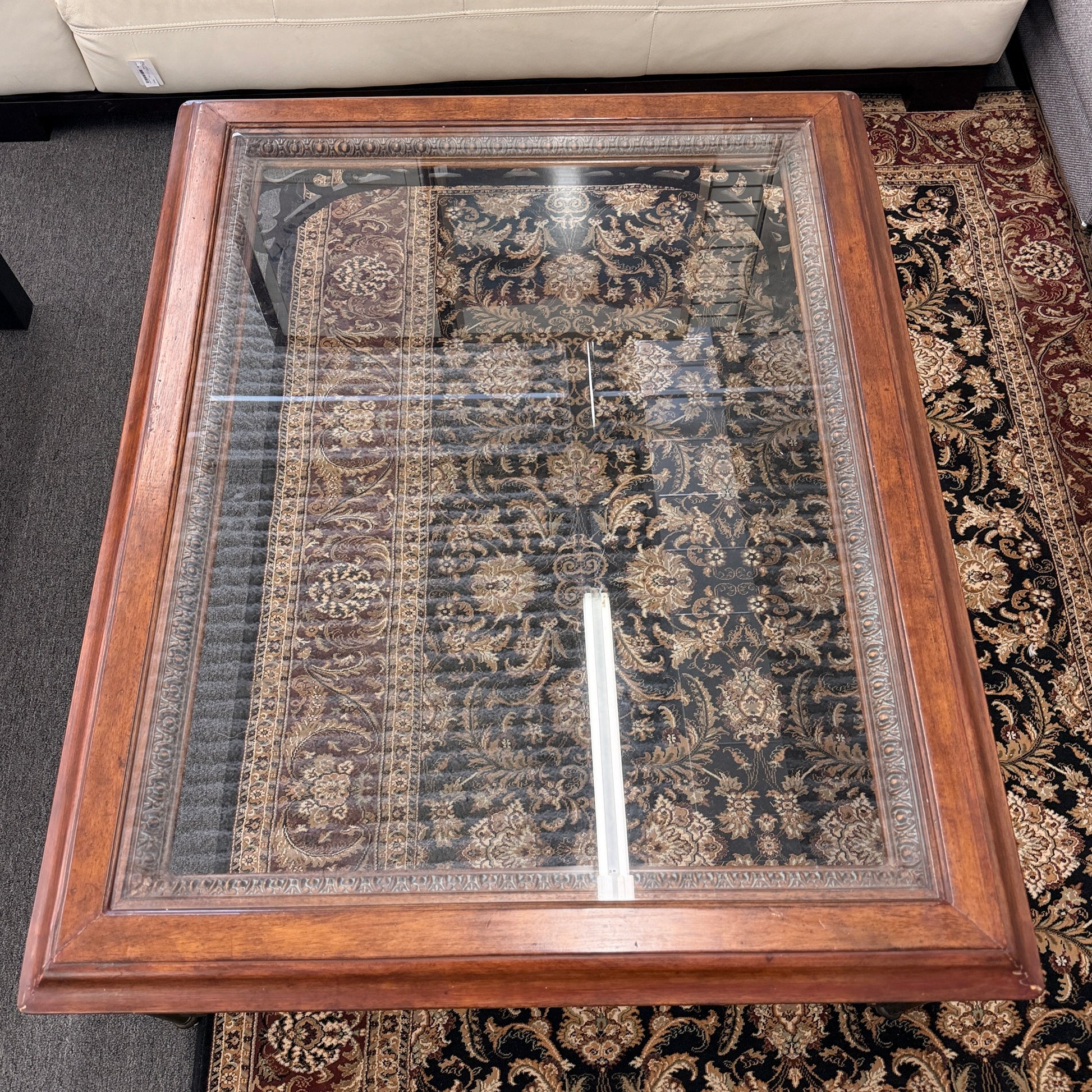 Square coffee table featuring a clear glass top insert, thick wooden frame, and an ornate scrolled metal base with traditional styling.