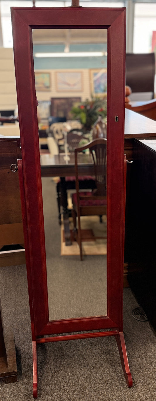 A full-length tilting floor mirror mounted in a wooden frame that opens into a locking internal jewelry armoire.