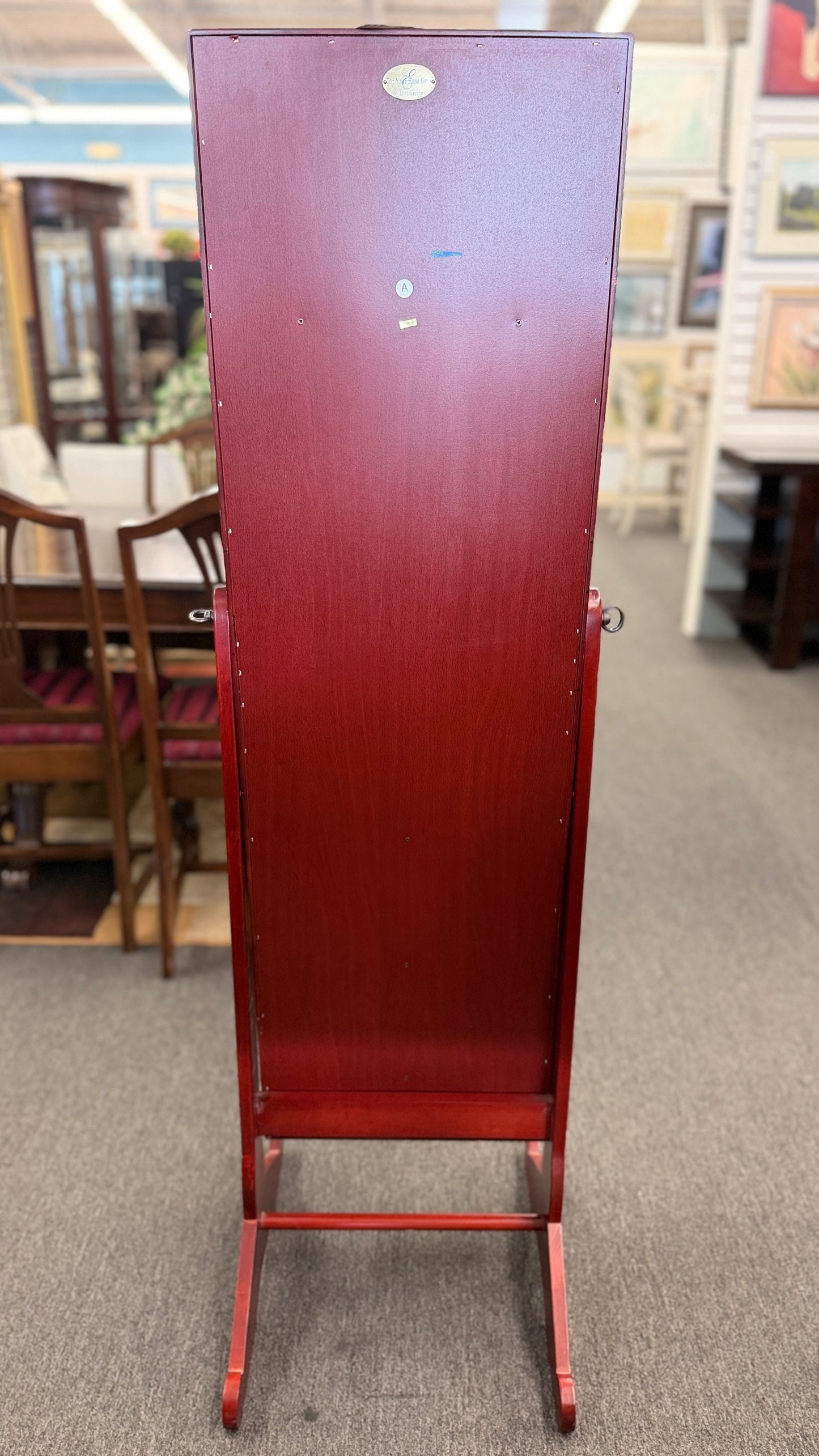 A full-length tilting floor mirror mounted in a wooden frame that opens into a locking internal jewelry armoire.
