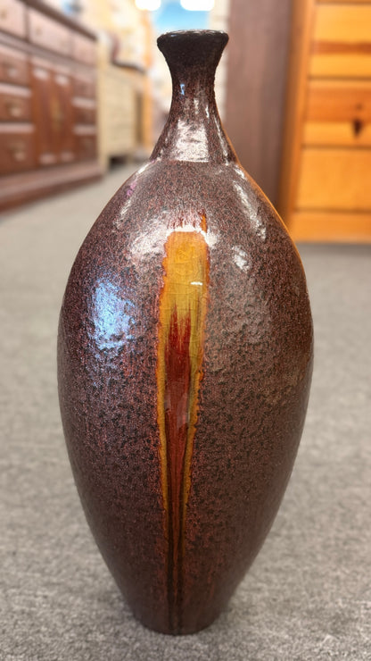 A tall teardrop-shaped ceramic vase featuring a textured mottled dark brown glaze with a vertical yellow and red-brown streak.