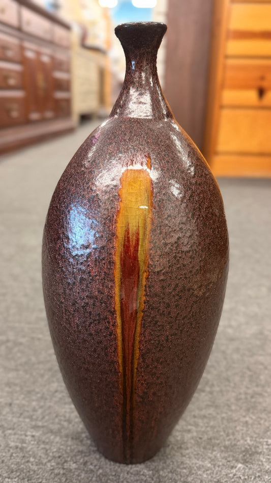 A tall teardrop-shaped ceramic vase featuring a textured mottled dark brown glaze with a vertical yellow and red-brown streak.