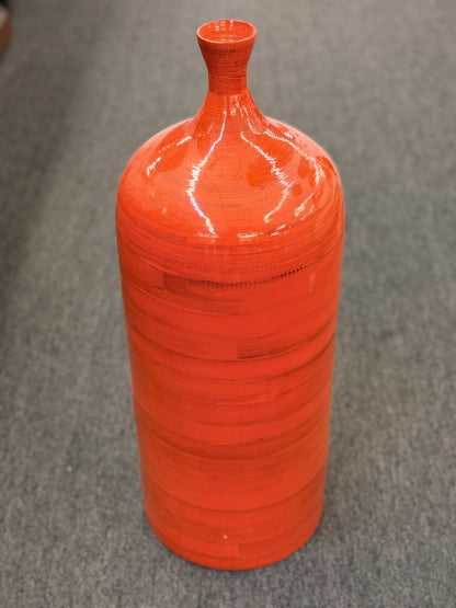 A tall slender ceramic floor vase with a narrow neck, vibrant glossy orange finish, and subtle horizontal ribbing in excellent condition.