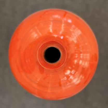 A tall slender ceramic floor vase with a narrow neck, vibrant glossy orange finish, and subtle horizontal ribbing in excellent condition.
