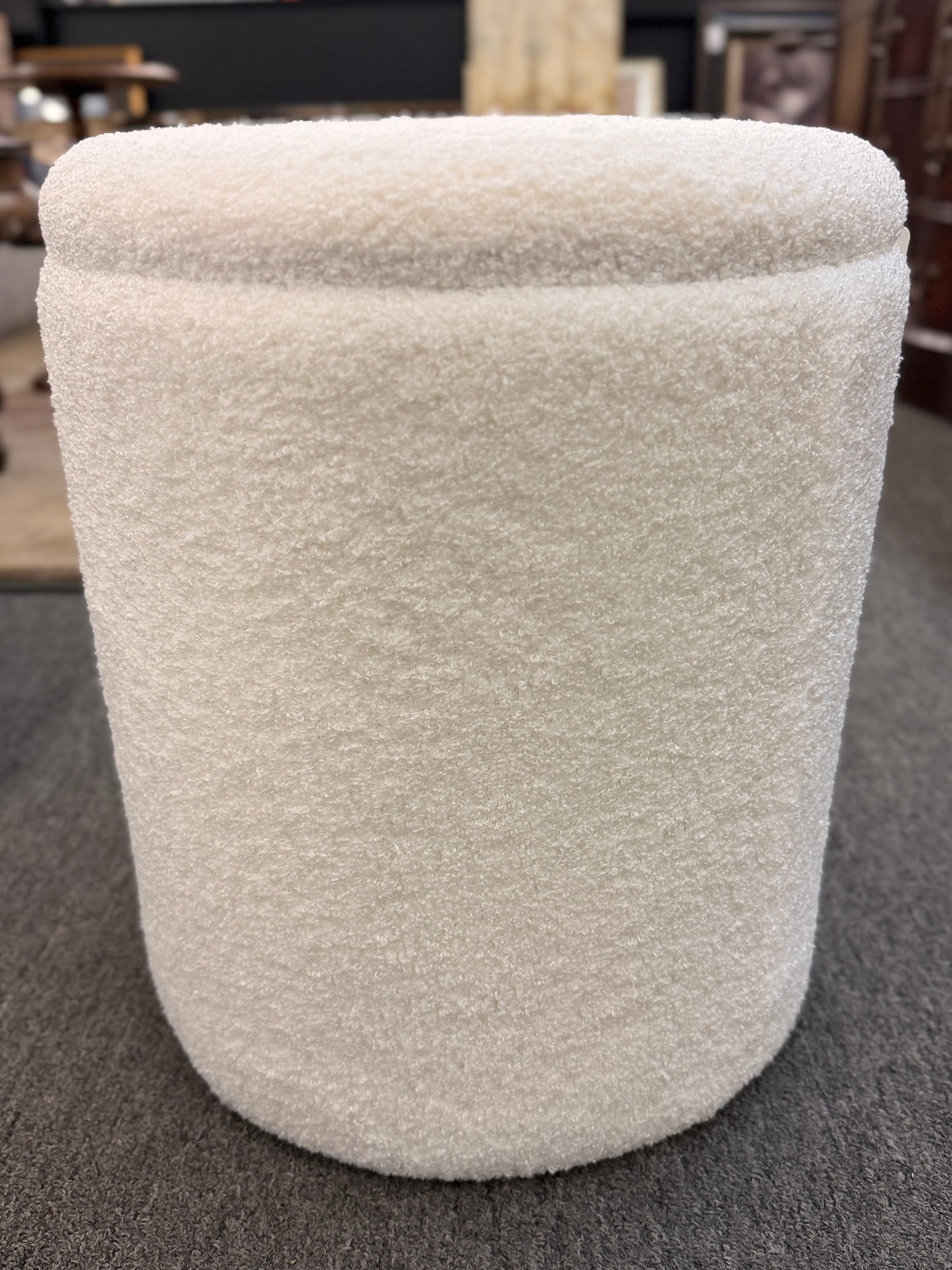 Round textured upholstered storage ottoman featuring a removable lid and hidden storage compartment, ideal as a footrest or extra seating.
