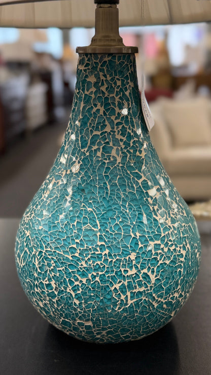 A teardrop-shaped ceramic table lamp with a textured teal and white crackle glaze base and a classic white pleated fabric lampshade.