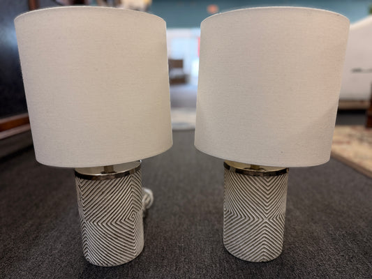 A pair of identical table lamps featuring textured white cylindrical ceramic bases with a geometric diamond pattern, white drum shades, and silver-toned hardware.