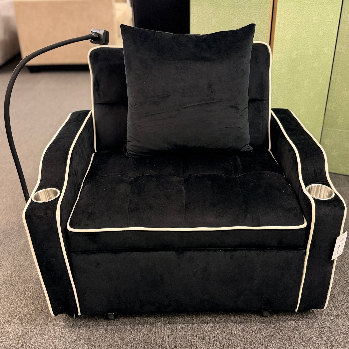 Plush theater-style sleeper chair upholstered in fabric with contrast piping, built-in cup holders, an adjustable reading light, and a matching throw pillow.