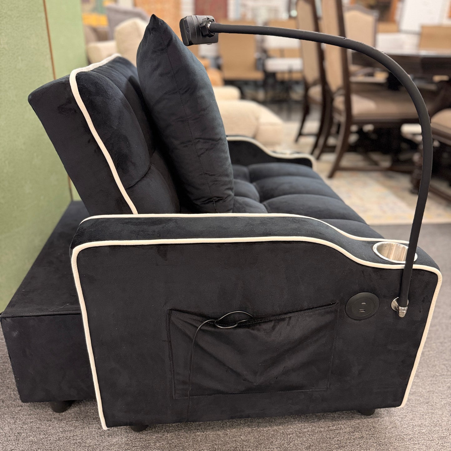 Plush theater-style sleeper chair upholstered in fabric with contrast piping, built-in cup holders, an adjustable reading light, and a matching throw pillow.