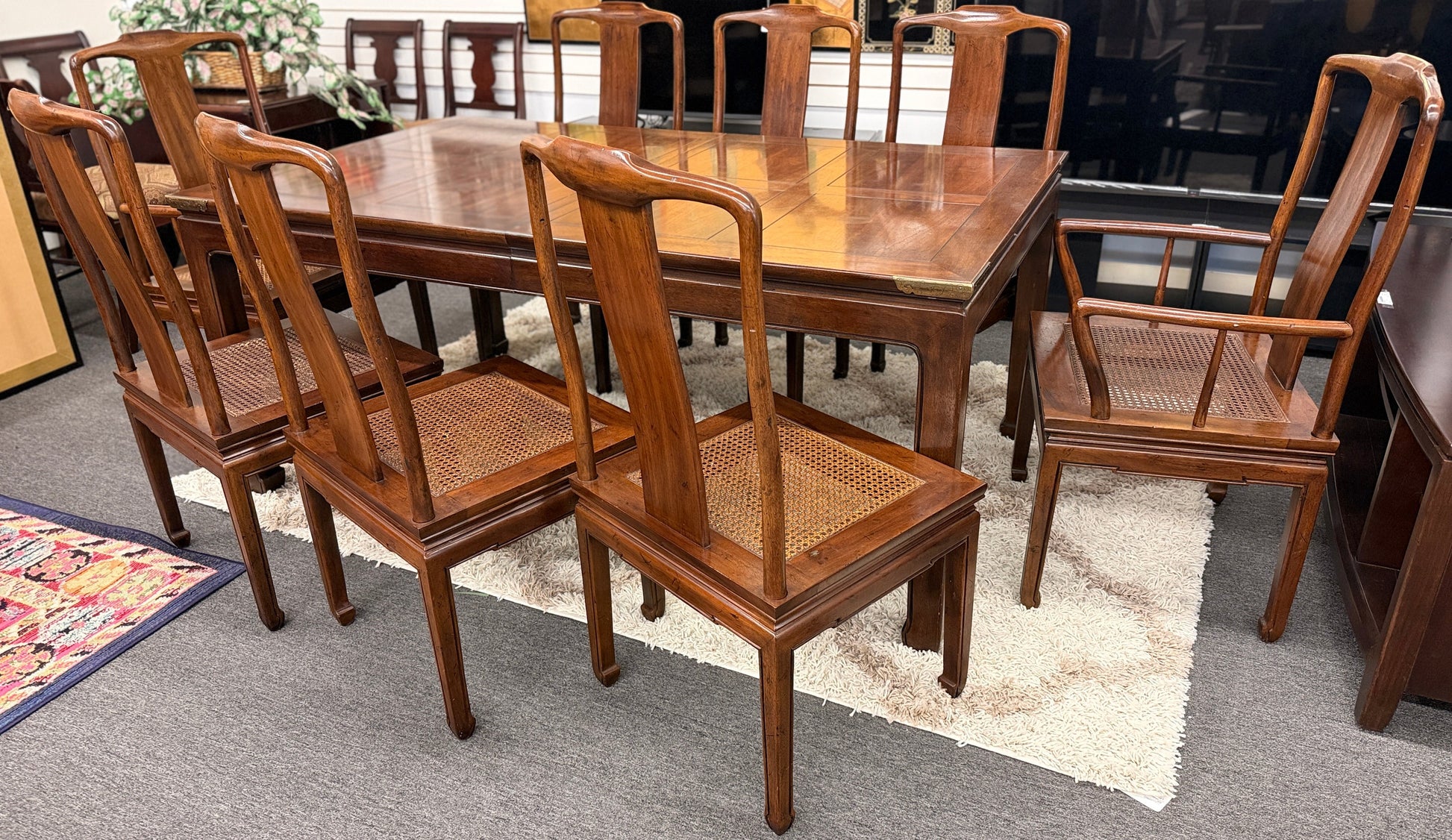 A 9-piece traditional wooden dining set featuring a large rectangular table, two matching armchairs, and six side chairs with woven rattan backrests.