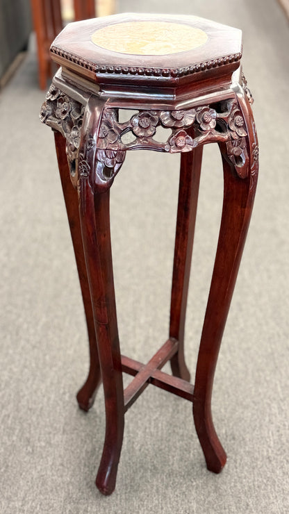A traditional Asian-style tall dark wood plant stand featuring a hexagonal marble inset top, pierced floral apron, and curved legs with an X-stretcher base in good condition.
