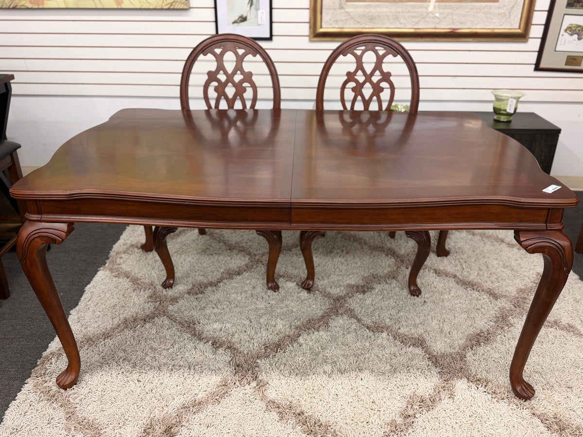 A traditional dark wood dining set including a rectangular table and four chairs with ornate backrests and light upholstered seats in excellent condition.