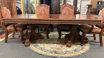 An ornate traditional dark wood dining table with wood-inlay details surrounded by six matching high-back chairs upholstered in red and gold damask fabric in excellent condition.