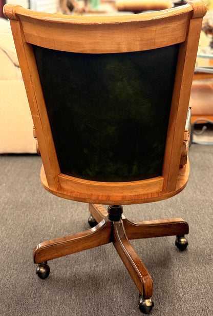 A traditional executive-style office desk chair with polished wood frame, deep forest green faux leather upholstery, brass nailhead trim, and a wheeled swivel base.