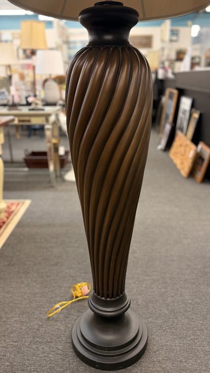 A tall floor lamp featuring a dark twisted pedestal base and a wide tan-colored fabric shade in excellent condition.