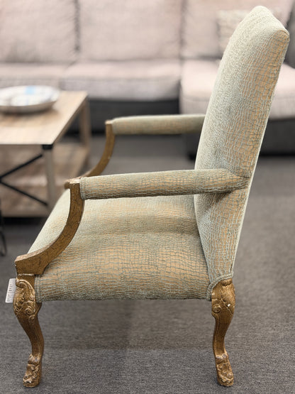 A high-back traditional accent armchair upholstered in a textured light-sage and gold fabric with gilded carved wooden arms, cabriole legs, and claw-and-ball feet in good condition.