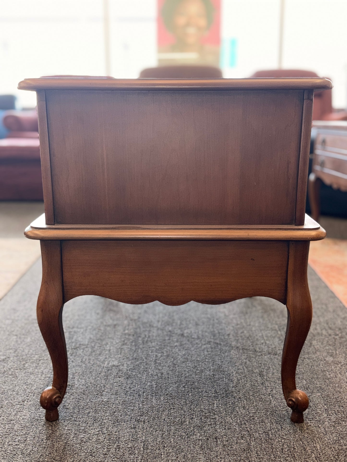 A wooden two-tiered step end table featuring decorative inlay with a gold border pattern, a single bottom drawer with ornate metal pulls, and cabriole legs.