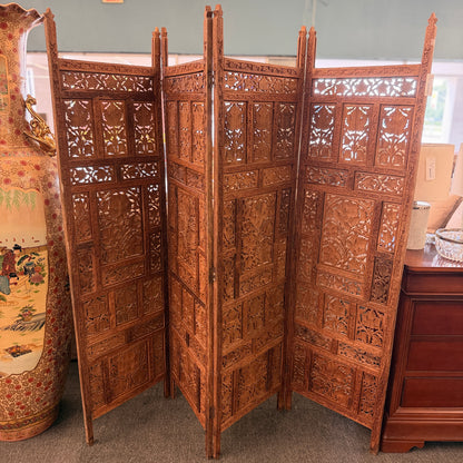 A decorative four-panel folding room divider with intricate openwork floral and geometric wood carvings in good condition.