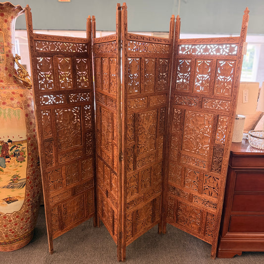 A decorative four-panel folding room divider with intricate openwork floral and geometric wood carvings in good condition.