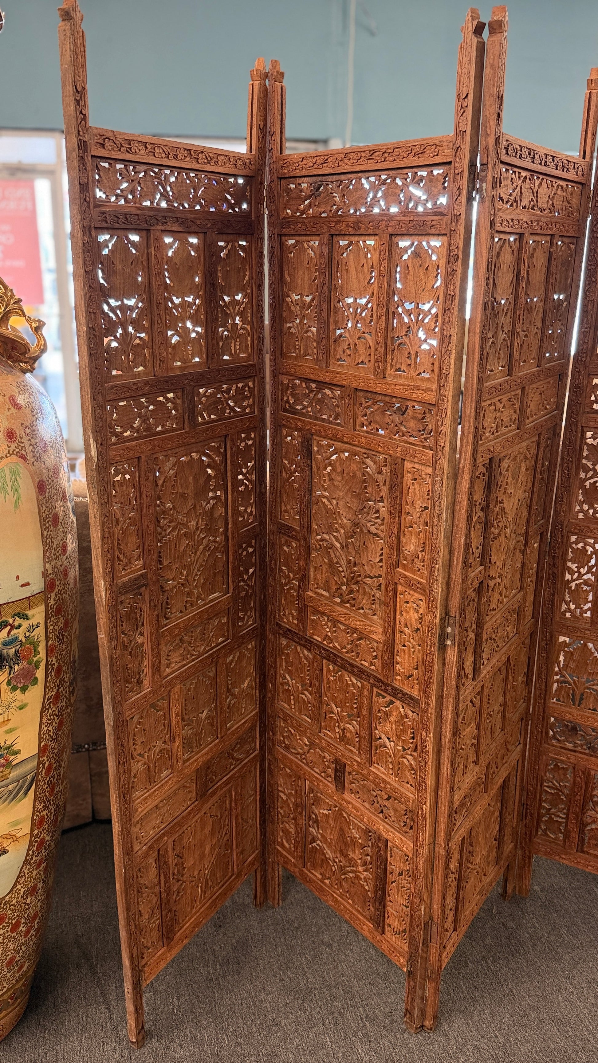 A decorative four-panel folding room divider with intricate openwork floral and geometric wood carvings in good condition.