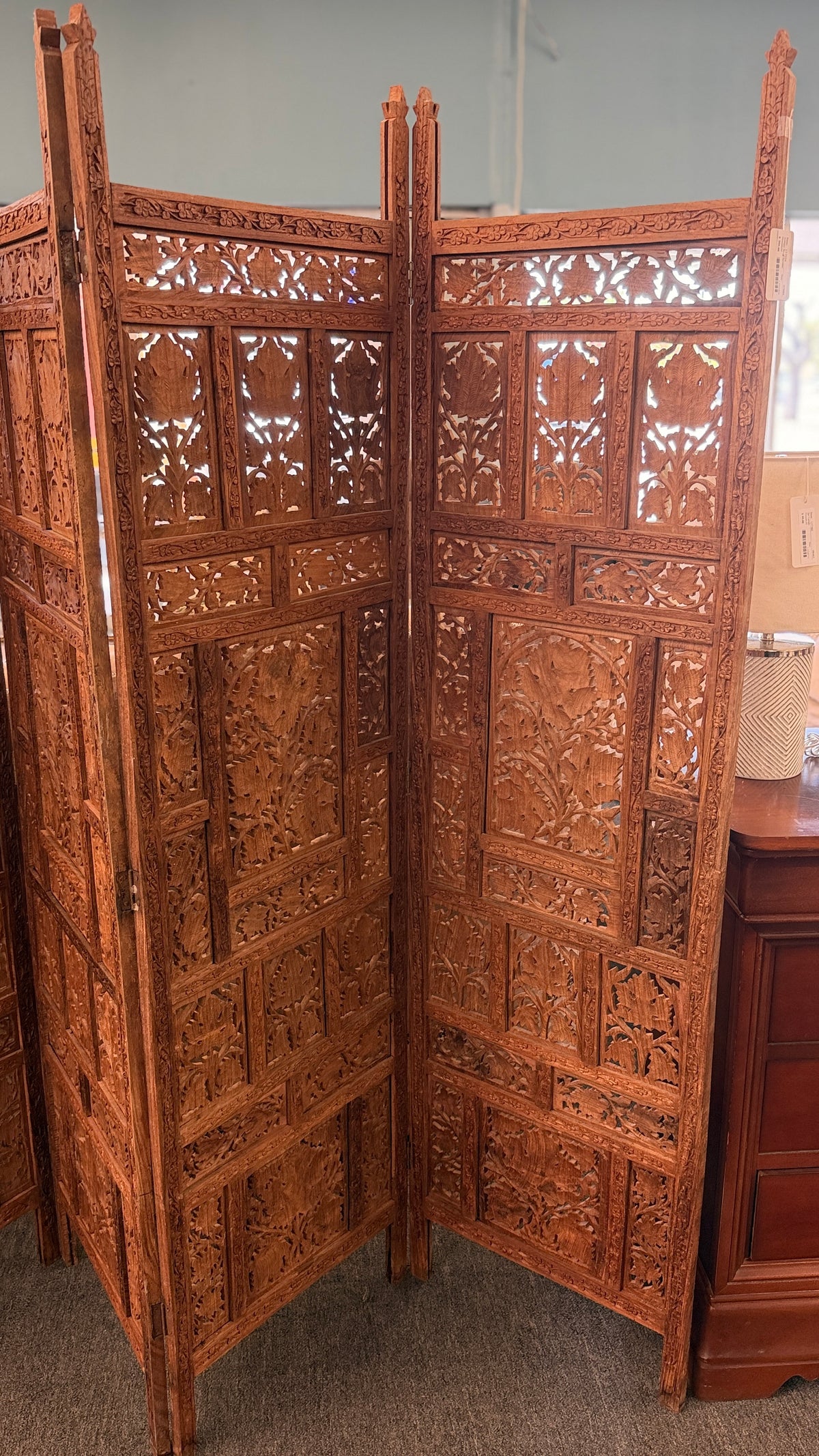A decorative four-panel folding room divider with intricate openwork floral and geometric wood carvings in good condition.