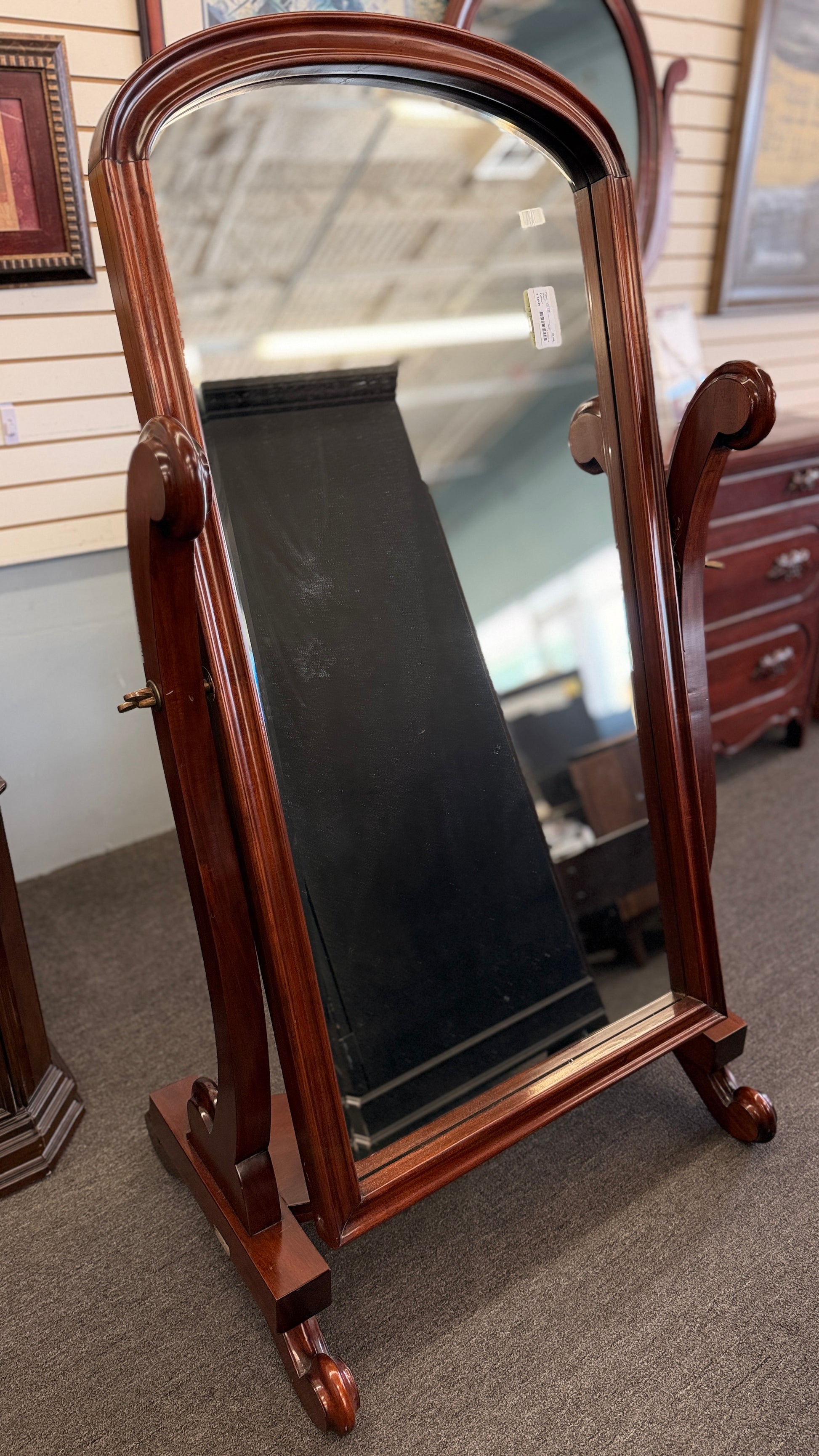Traditional freestanding oval cheval mirror with a polished wood frame, adjustable full-length mirror, decorative scrolled legs, and a sturdy wooden base.