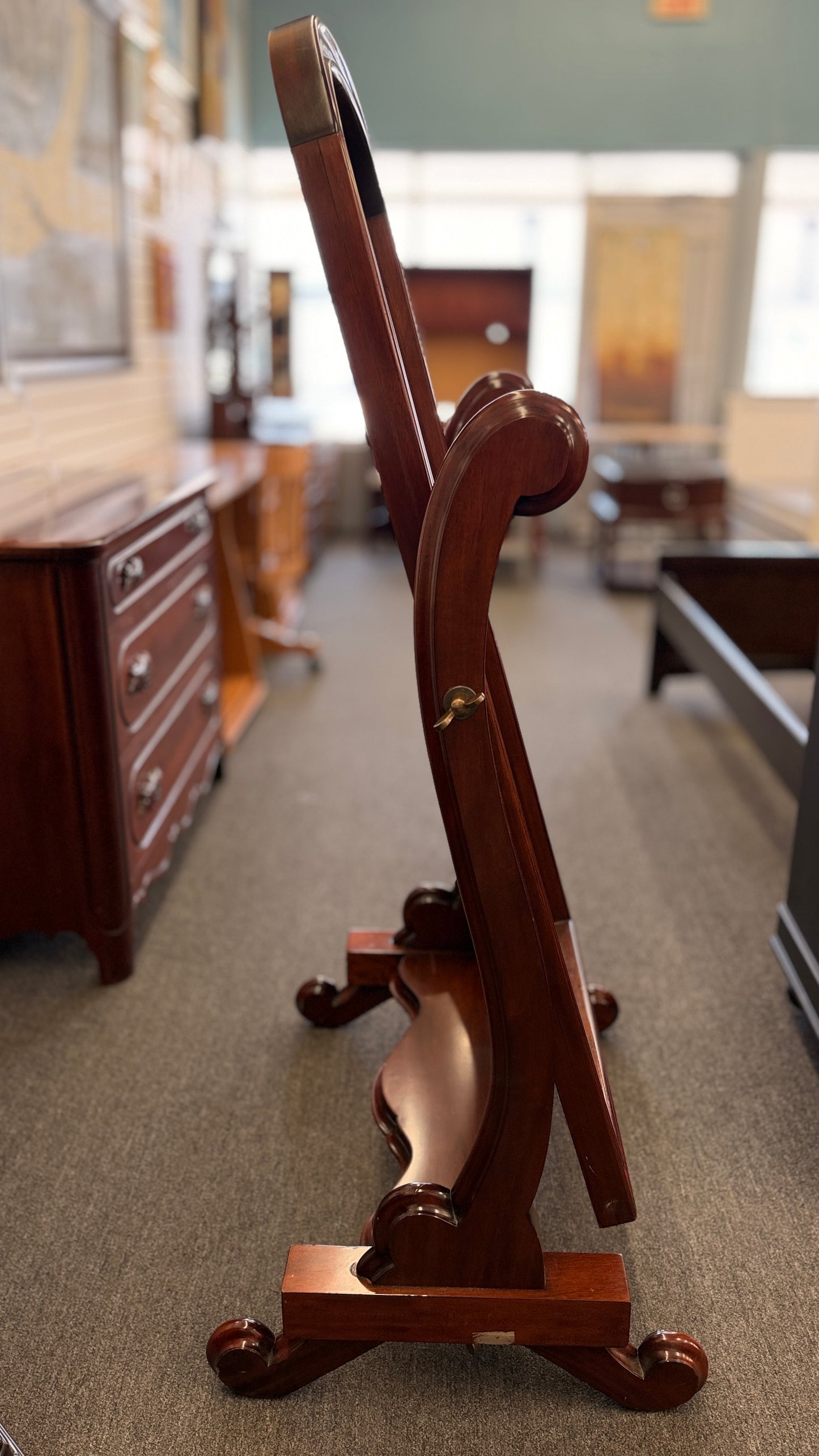 Traditional freestanding oval cheval mirror with a polished wood frame, adjustable full-length mirror, decorative scrolled legs, and a sturdy wooden base.
